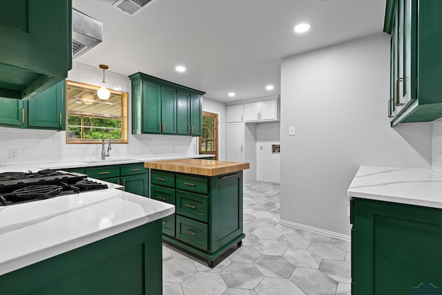 kitchen with green cabinetry, recessed lighting, visible vents, and a sink