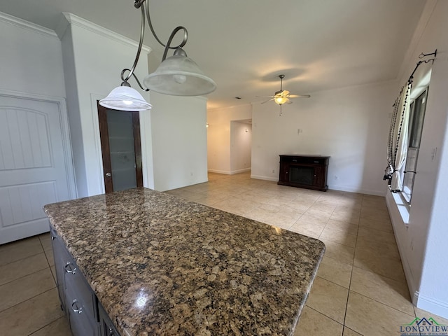 kitchen with a center island, dark stone counters, ceiling fan, light tile patterned floors, and decorative light fixtures