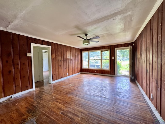 313 Millie St, Longview, TX 75602 - unfurnished room featuring a textured ceiling, wood-type flooring, a ceiling fan, wooden walls, and ornamental molding