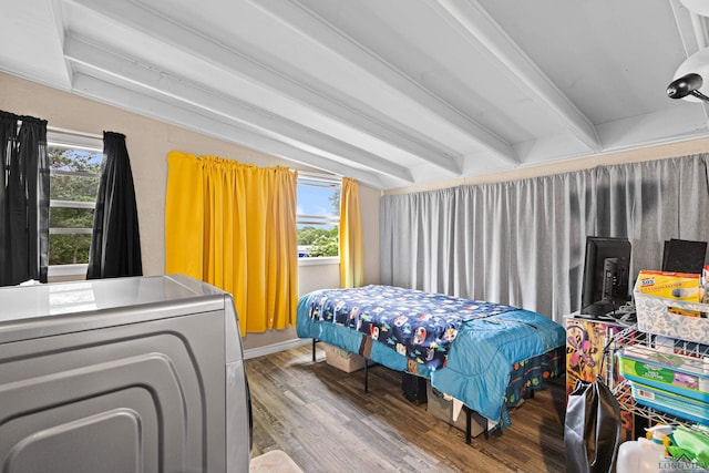 bedroom featuring lofted ceiling with beams, multiple windows, wood finished floors, and washer / dryer