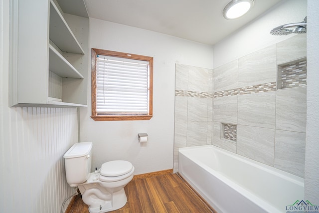 bathroom featuring wood-type flooring, tiled shower / bath, and toilet