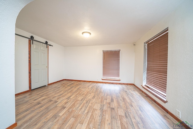 spare room with wood-type flooring and a barn door