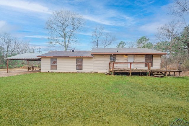 back of property with a wooden deck, a yard, and a carport