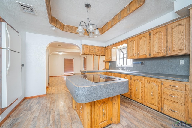 kitchen with black electric cooktop, a tray ceiling, light hardwood / wood-style flooring, and a textured ceiling