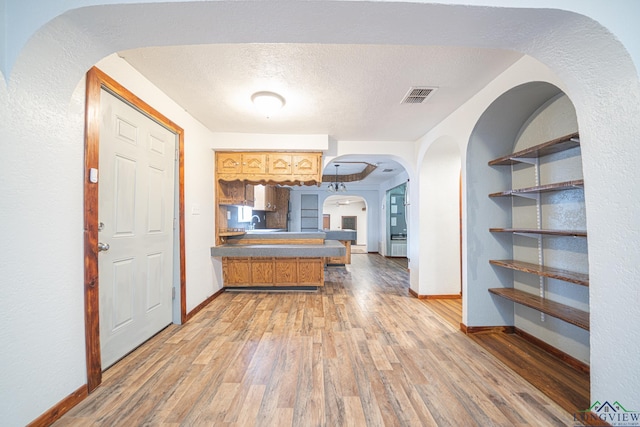 kitchen featuring a textured ceiling and light hardwood / wood-style floors