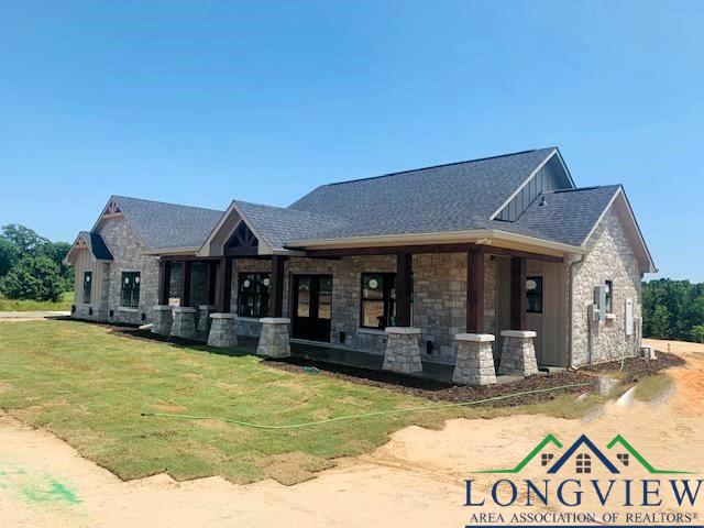 265 Fm 995, Atlanta, TX 75551 - view of front of home with board and batten siding, a shingled roof, a front lawn, and stone siding