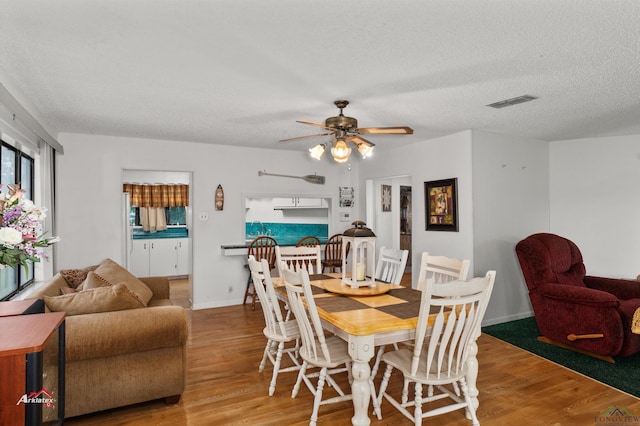 dining space with ceiling fan, a textured ceiling, and hardwood / wood-style flooring