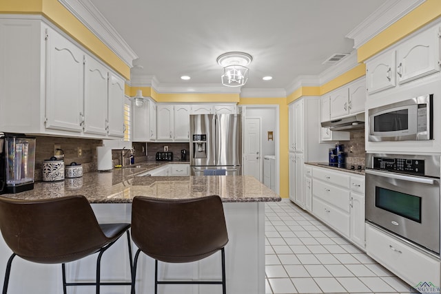 kitchen featuring appliances with stainless steel finishes, a breakfast bar, backsplash, and kitchen peninsula