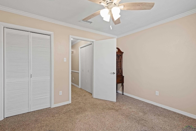 unfurnished bedroom featuring crown molding, light colored carpet, ceiling fan, and a closet