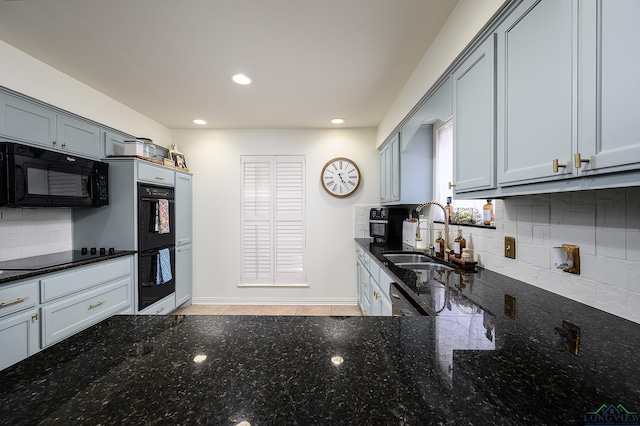 kitchen with tasteful backsplash, recessed lighting, a sink, dark stone countertops, and black appliances