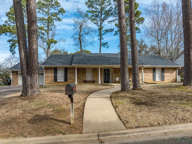 single story home featuring a garage, brick siding, and a shingled roof