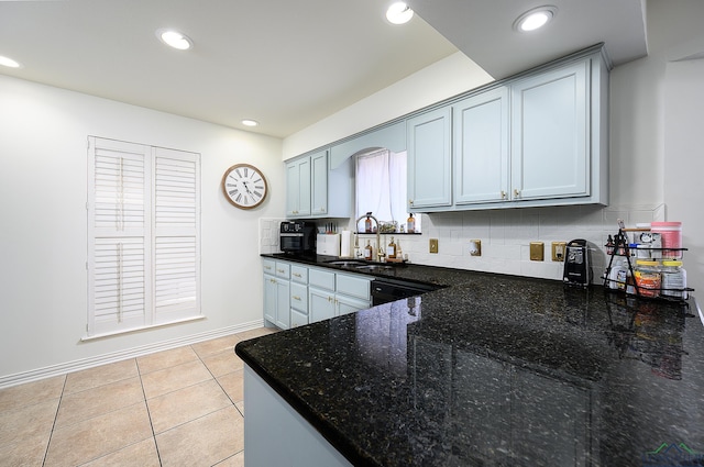 kitchen featuring light tile patterned floors, recessed lighting, a sink, dark stone counters, and tasteful backsplash