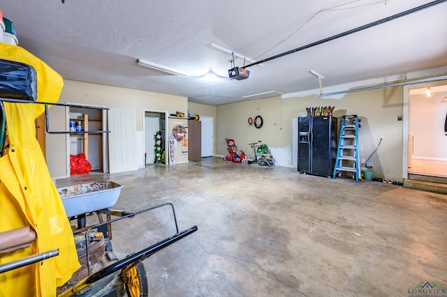 garage featuring a garage door opener and black refrigerator with ice dispenser