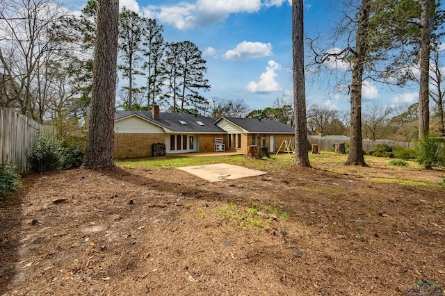 view of front of house with a patio, brick siding, a chimney, and fence