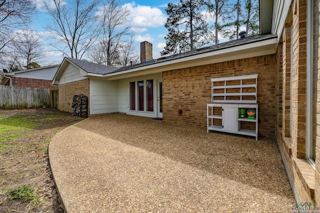 back of property featuring a patio, a chimney, fence, french doors, and brick siding