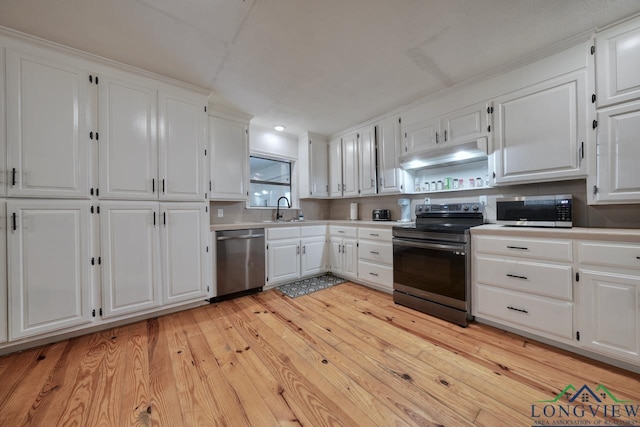 kitchen with stainless steel appliances, sink, white cabinets, and light hardwood / wood-style flooring