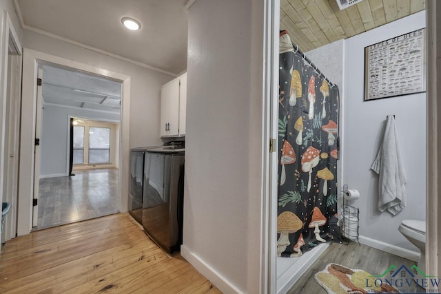 hall with ornamental molding, separate washer and dryer, and light wood-type flooring