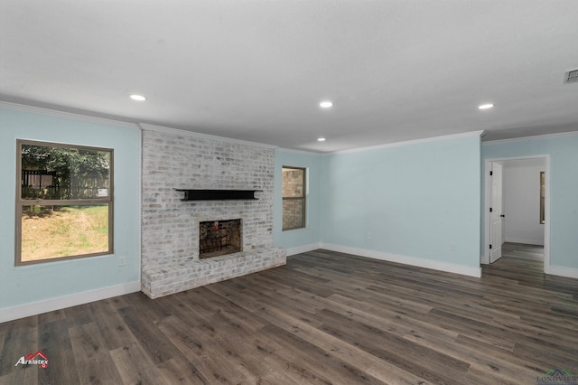 unfurnished living room with a brick fireplace, dark hardwood / wood-style flooring, and crown molding