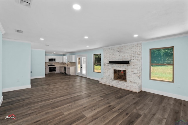 unfurnished living room featuring sink, a brick fireplace, dark hardwood / wood-style flooring, and crown molding