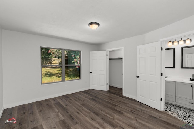 unfurnished bedroom featuring a closet, dark wood-type flooring, sink, and connected bathroom