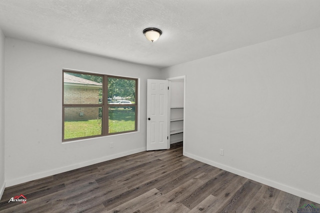 spare room featuring a textured ceiling and dark hardwood / wood-style flooring