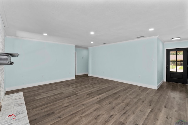 unfurnished living room featuring a brick fireplace, dark hardwood / wood-style flooring, and ornamental molding