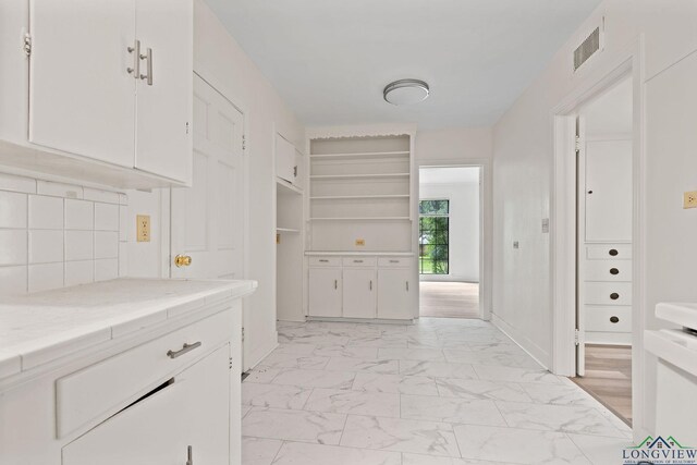 interior space with backsplash and white cabinetry