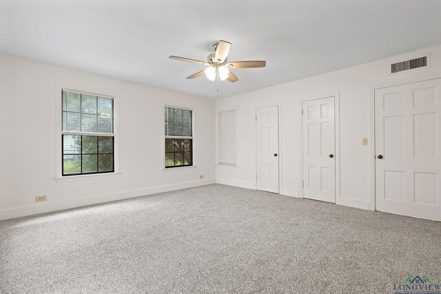 unfurnished bedroom with carpet flooring, multiple closets, and ceiling fan