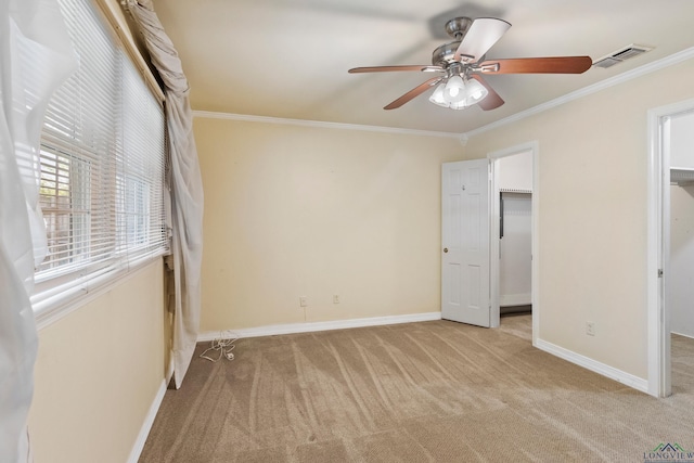 unfurnished bedroom with ceiling fan, a spacious closet, ornamental molding, and a closet