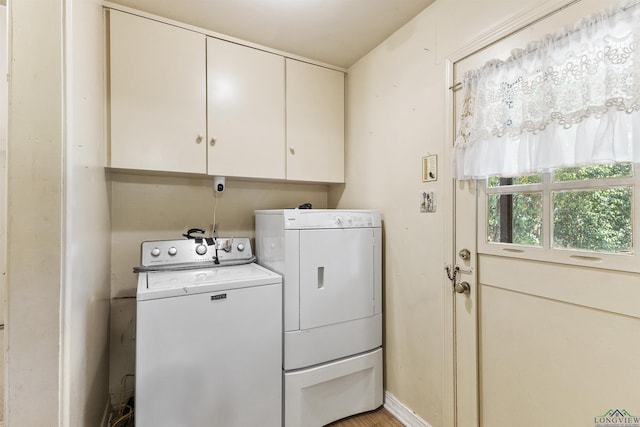 clothes washing area with cabinets and washing machine and clothes dryer