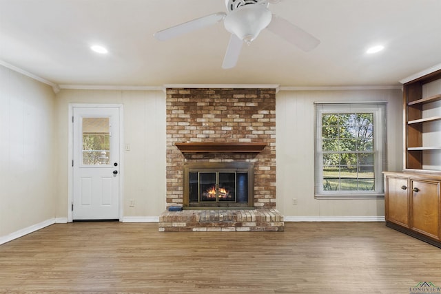 unfurnished living room with crown molding, ceiling fan, light wood-type flooring, and a brick fireplace