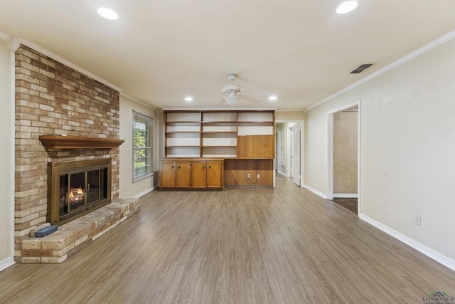 unfurnished living room with a fireplace, hardwood / wood-style flooring, ceiling fan, and crown molding