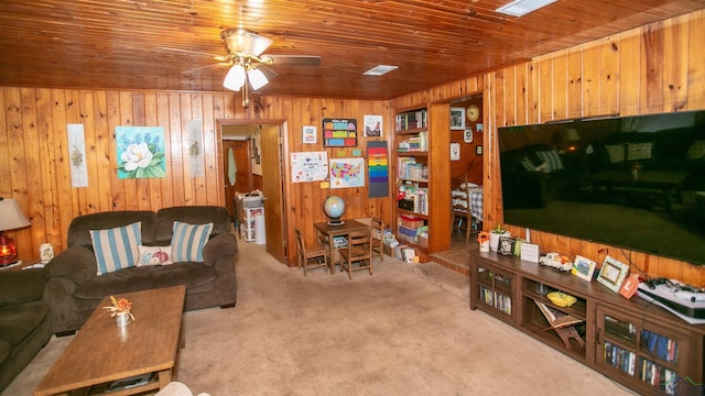 living room with ceiling fan, wood ceiling, wood walls, and light carpet