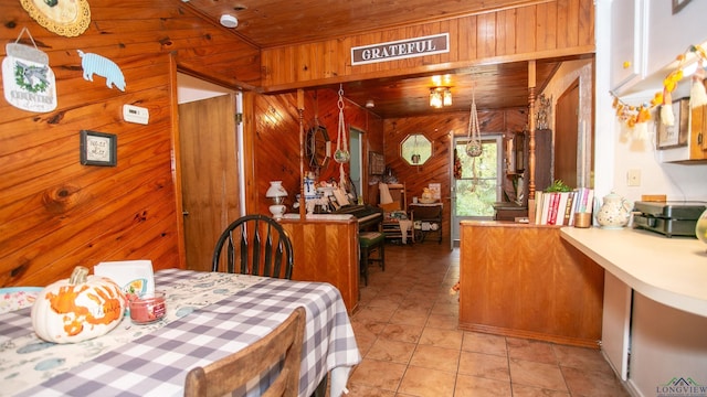 dining area featuring wood walls, light tile patterned flooring, and wooden ceiling