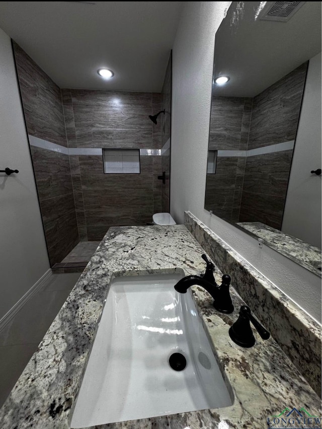 bathroom with a tile shower and vanity