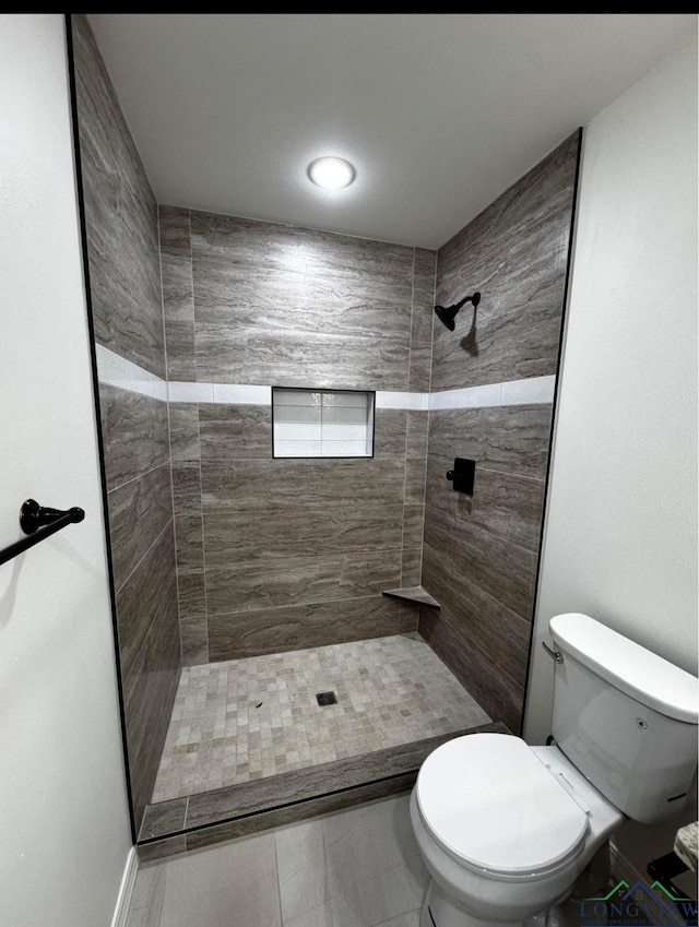 bathroom featuring tiled shower and toilet