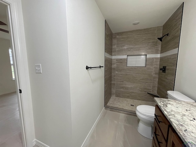 bathroom with tiled shower, vanity, and toilet