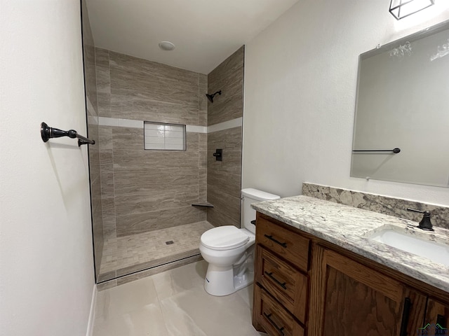 bathroom with vanity, a tile shower, and toilet