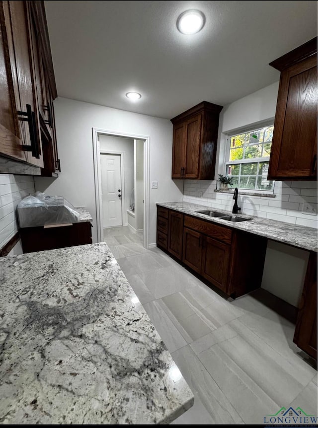 kitchen with light stone counters, sink, and dark brown cabinets