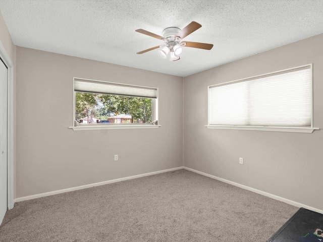 carpeted empty room featuring ceiling fan and a textured ceiling