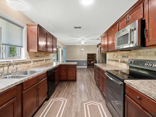 kitchen featuring sink, light hardwood / wood-style flooring, ceiling fan, decorative backsplash, and appliances with stainless steel finishes