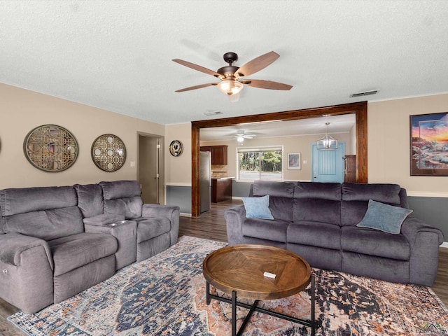 living room featuring ceiling fan, wood-type flooring, and a textured ceiling