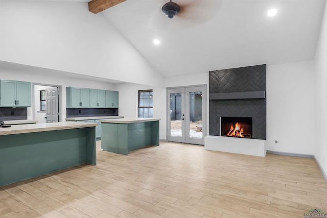 kitchen with light hardwood / wood-style flooring, beamed ceiling, high vaulted ceiling, a fireplace, and a breakfast bar