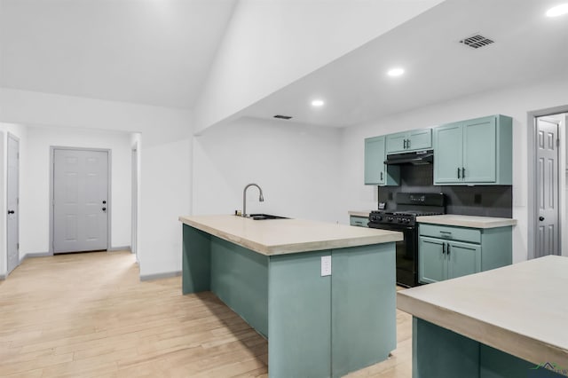 kitchen featuring sink, black gas range oven, tasteful backsplash, lofted ceiling, and a center island with sink