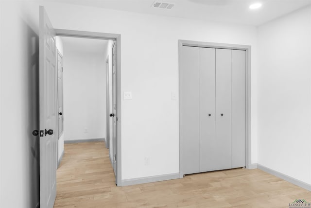 unfurnished bedroom with light wood-type flooring and a closet