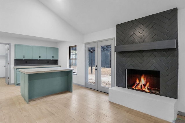 kitchen featuring a breakfast bar, french doors, light hardwood / wood-style flooring, blue cabinetry, and a fireplace