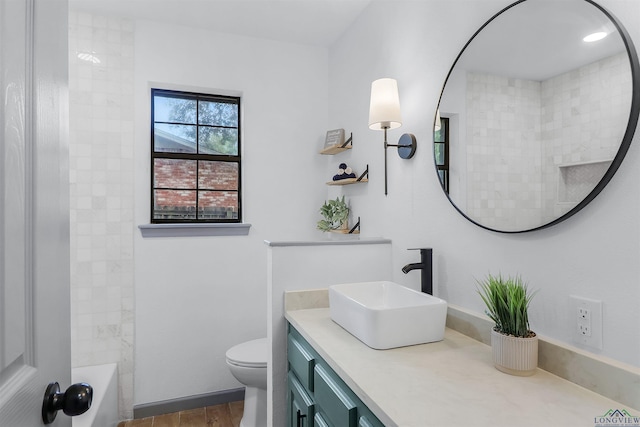 full bathroom with hardwood / wood-style floors, vanity, tiled shower / bath combo, and toilet