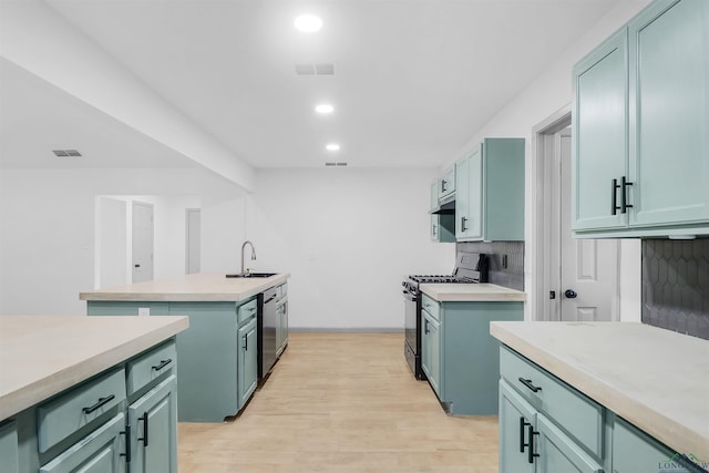 kitchen with gas stove, dishwasher, sink, backsplash, and green cabinetry