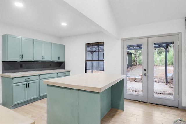 kitchen featuring a center island, french doors, green cabinets, light hardwood / wood-style flooring, and tasteful backsplash