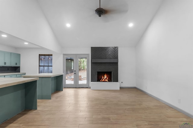 kitchen featuring french doors, a large fireplace, ceiling fan, high vaulted ceiling, and light hardwood / wood-style floors